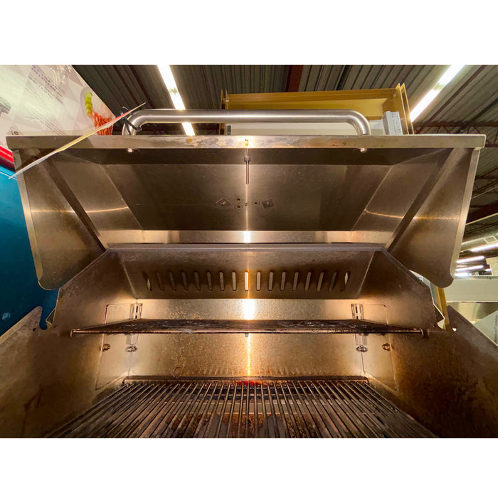 Stainless steel outdoor grill with a large hood in an industrial setting