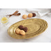 An oval gold serving platter with a textured concentric-ring pattern, styled on a white marble surface with cookies, a glass of lemonade, and wooden cutlery.
